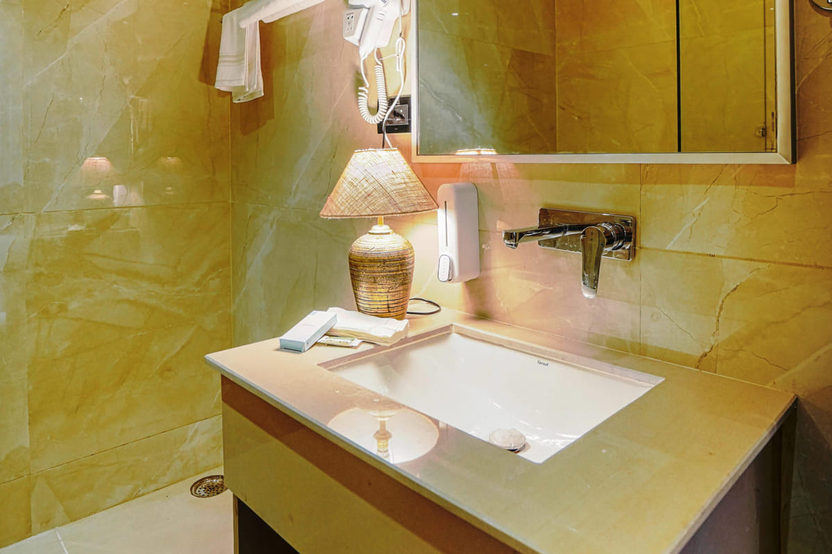 The bathroom of a Deluxe room at Escala Hotel, with a washbasin set into a stone counter, a mirror