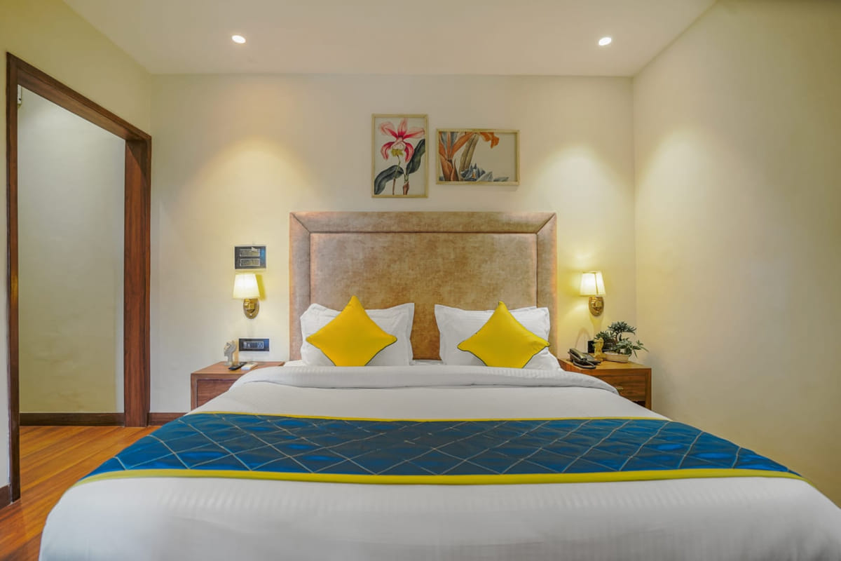 A Deluxe room at Escala Hotel, with a padded beige headboard, yellow cushions, a blue and yellow bed runner
