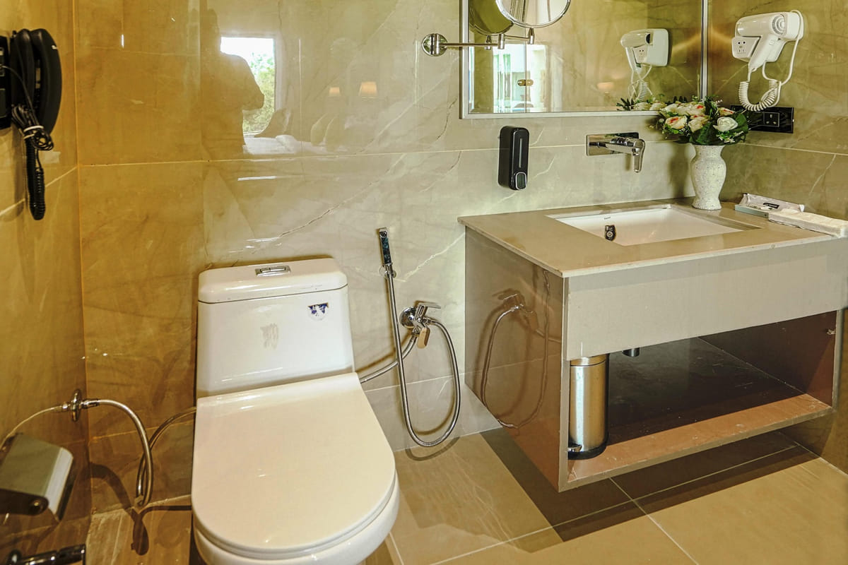 The bathroom of a Suite at Escala Hotel, with a washbasin set into a stone counter, a mirror