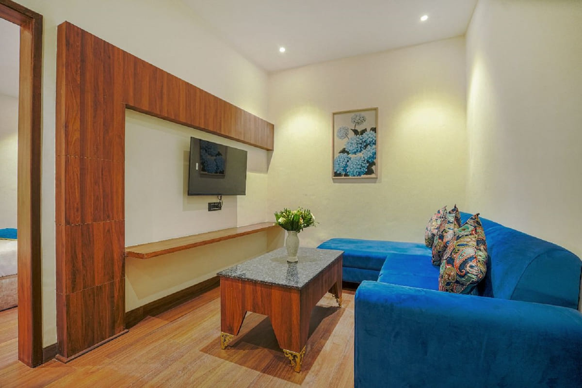 The living area of a Suite at Escala Hotel, with a blue sofa, a wall-mounted television on the timber panel