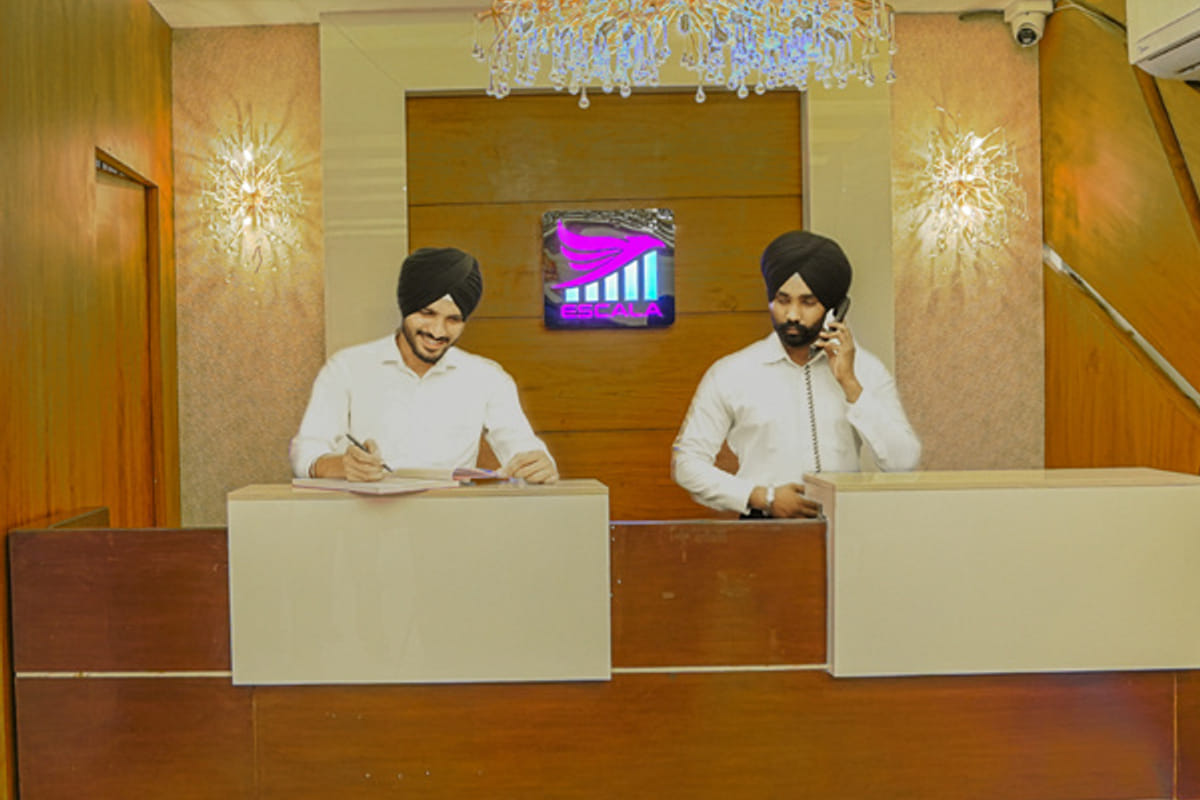 The reception at Escala Hotel, with two members of staff behind the timber counter