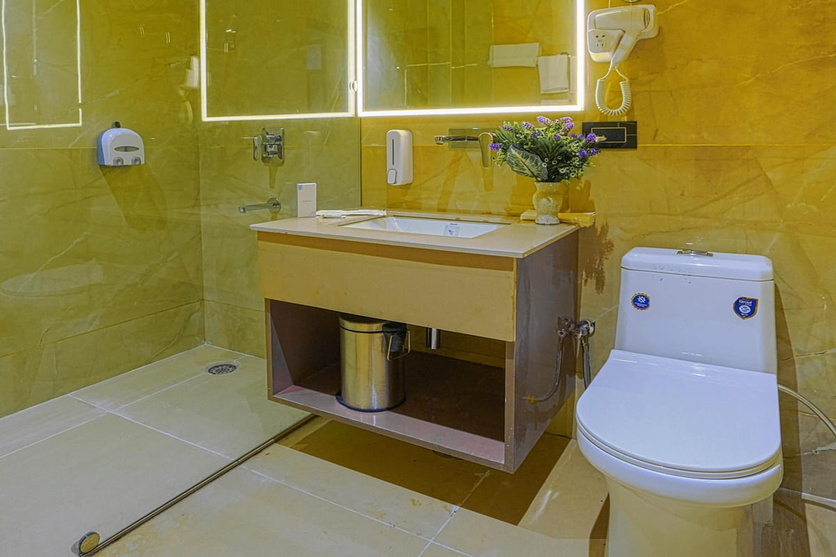 The bathroom of a Super Deluxe room at Escala Hotel, with a washbasin under a lit mirror