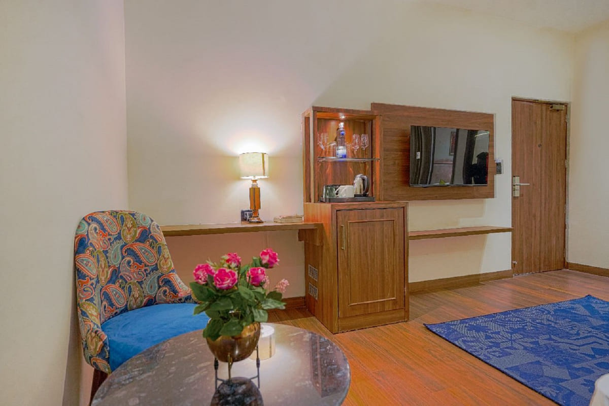 The seating corner of a Super Deluxe room at Escala Hotel, with a patterned armchair, flowers on the table