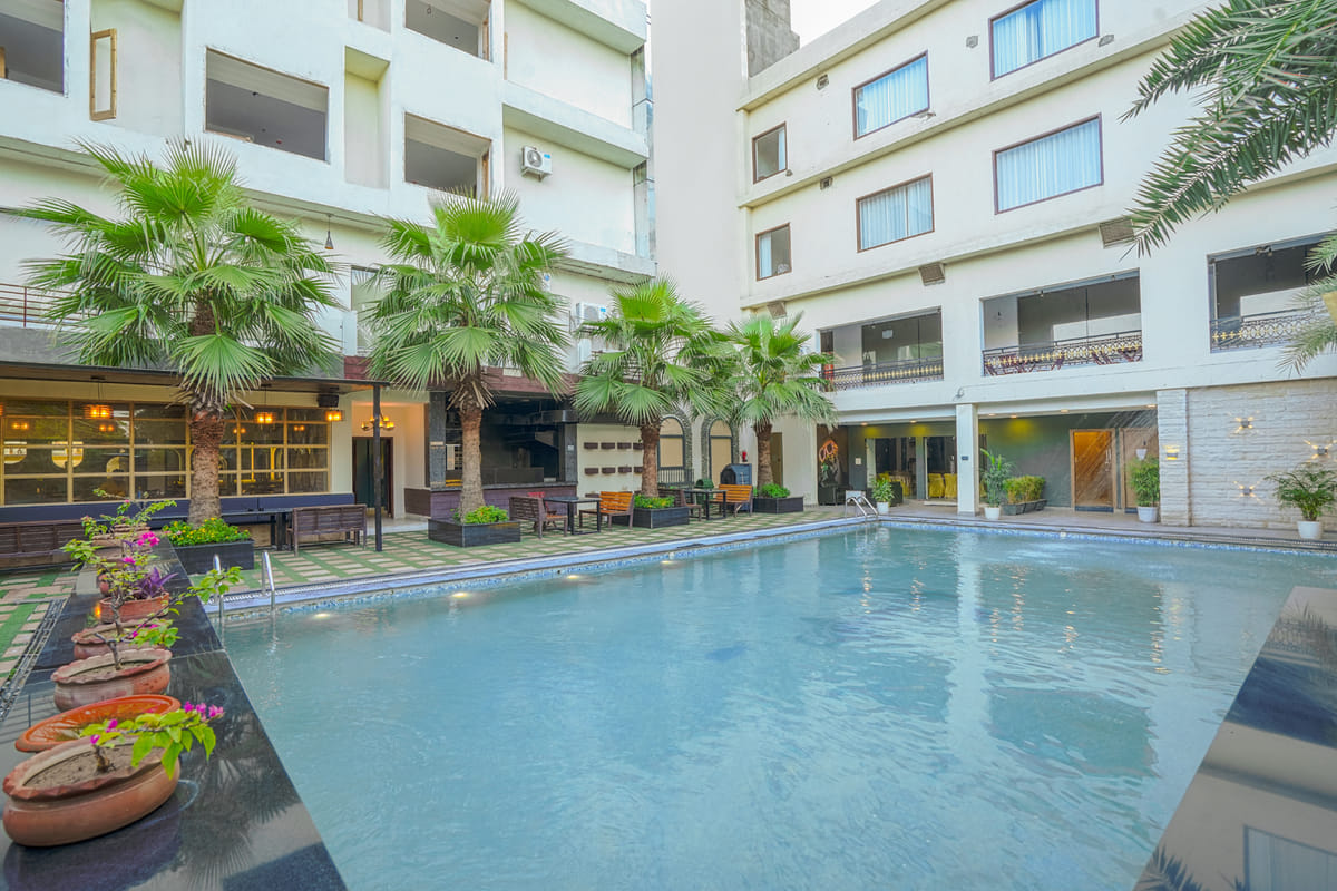 The swimming pool at Escala Hotel, set in a planted courtyard with palms along the edge and the hotel rising on the far side
