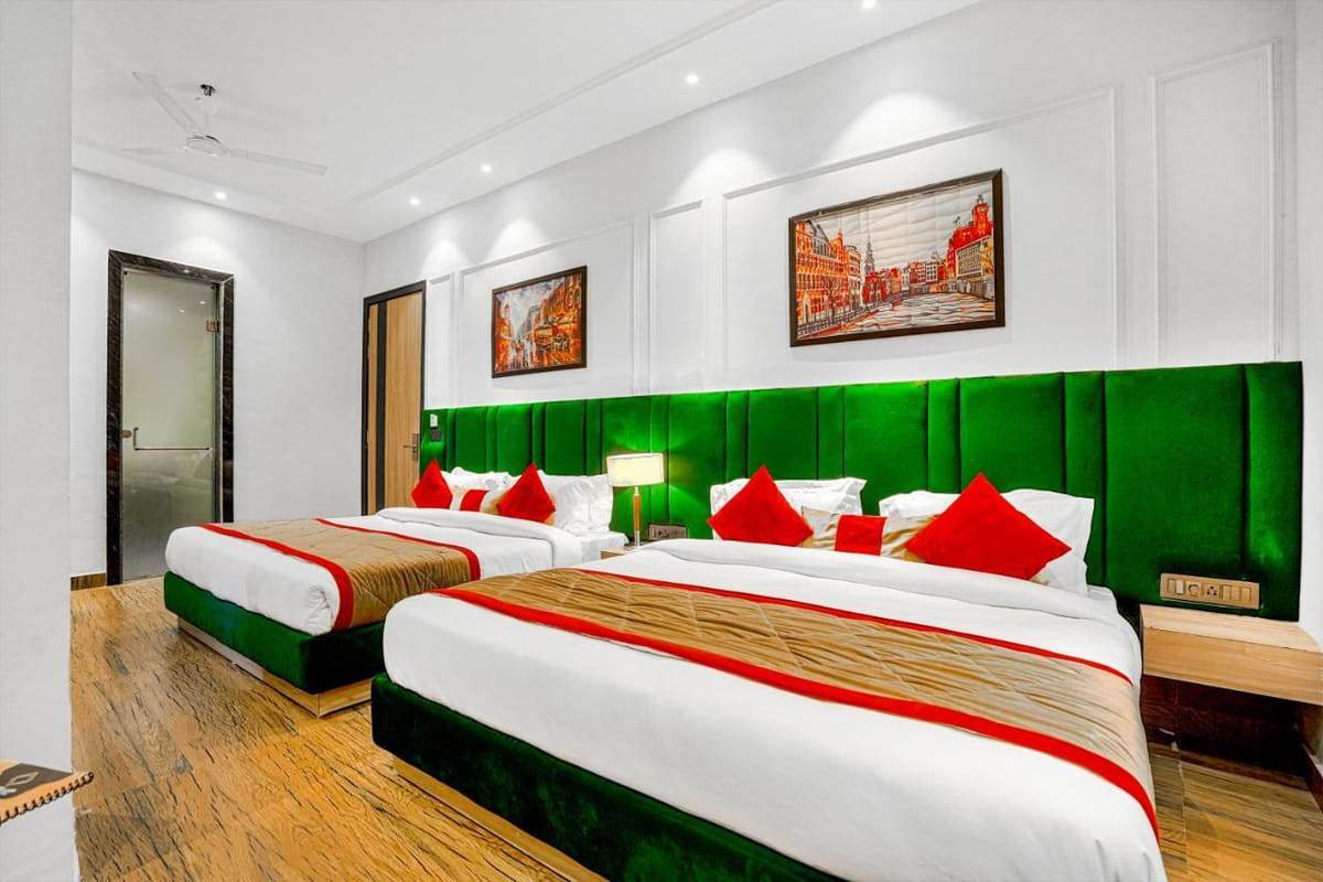 A Family Room at Grand Cabbana, with two beds side by side against green padded headboards and framed artwork hung