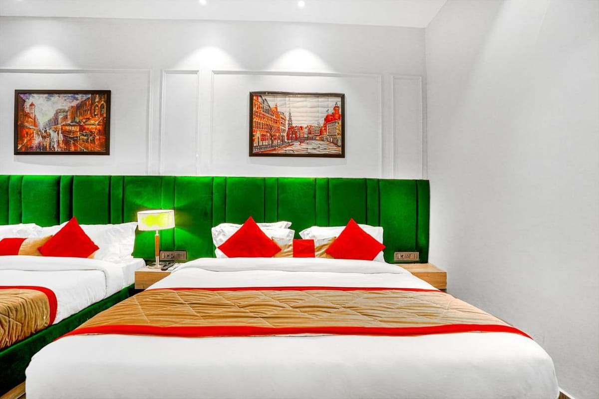 A Family Room at Grand Cabbana, with two beds against green padded headboards, a lamp between them