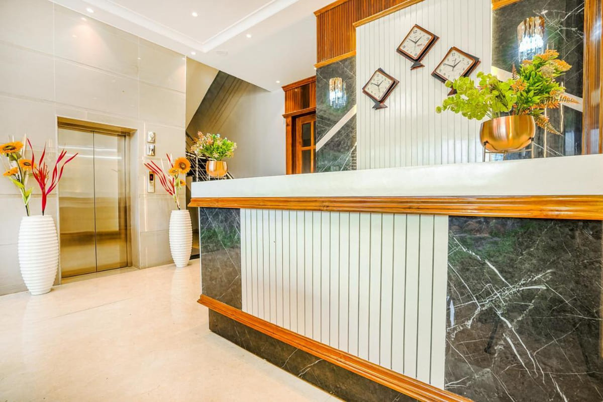 The reception counter at Grand Cabbana beside the lift, with tall vases of flowers at either end and wall clocks