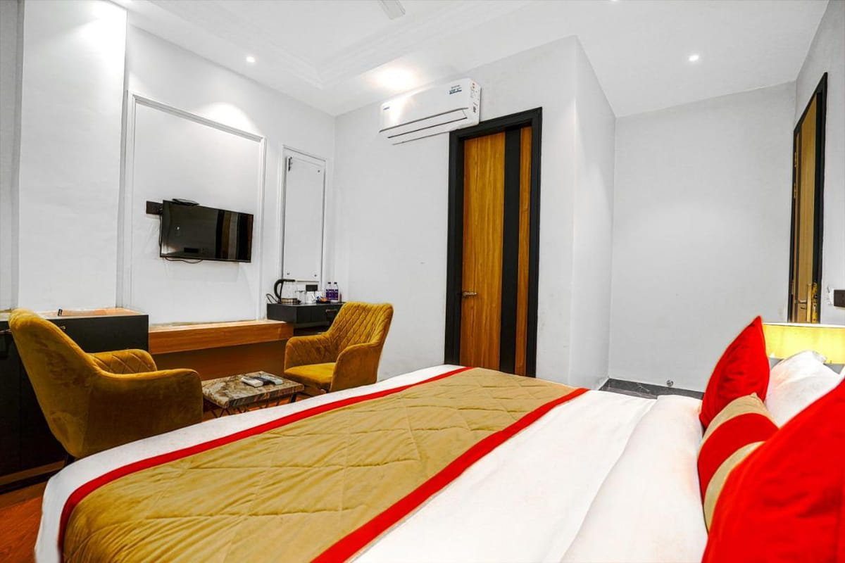 A Super Deluxe room at Grand Cabbana, with a wall-mounted television opposite the bed and two yellow armchairs