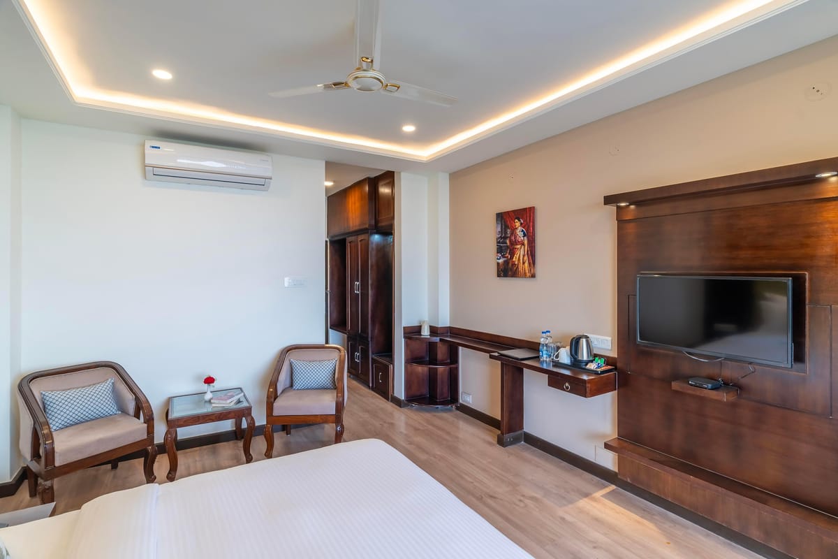 A Deluxe room with valley view at Hotel Karnika, with two armchairs around a small table, a wardrobe