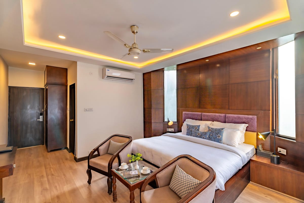 The Maharaja Suite at Hotel Karnika, with a mauve padded headboard and a pair of carved armchairs