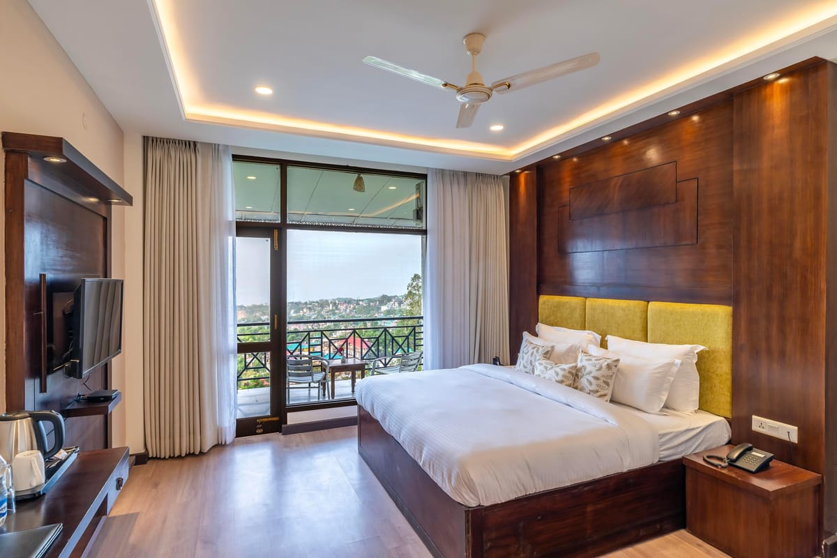 The Maharaja Suite at Hotel Karnika, with a yellow padded headboard, a television opposite