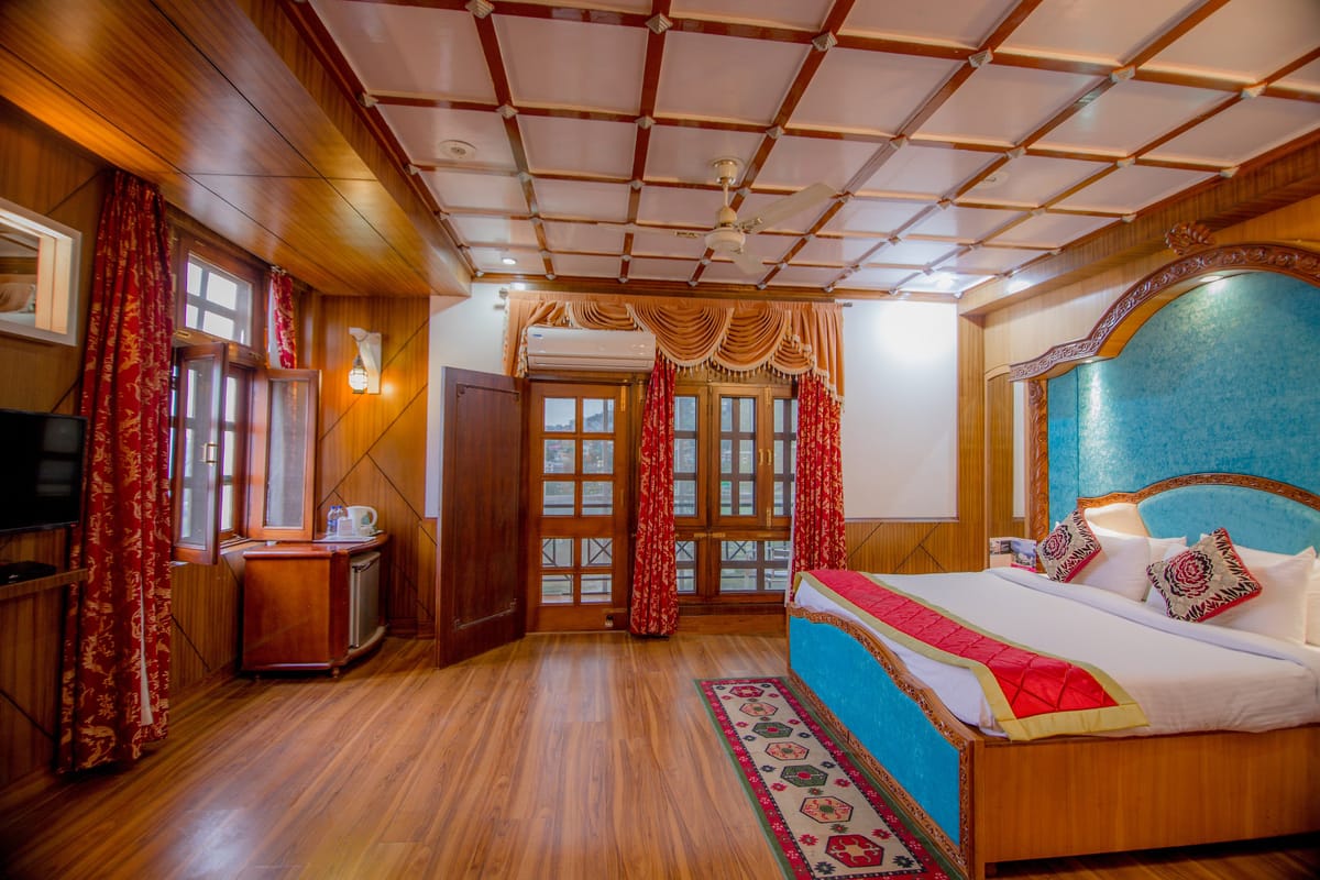 The Maharani Suite at Hotel Karnika, with a coffered timber ceiling, red curtains and a carved bed