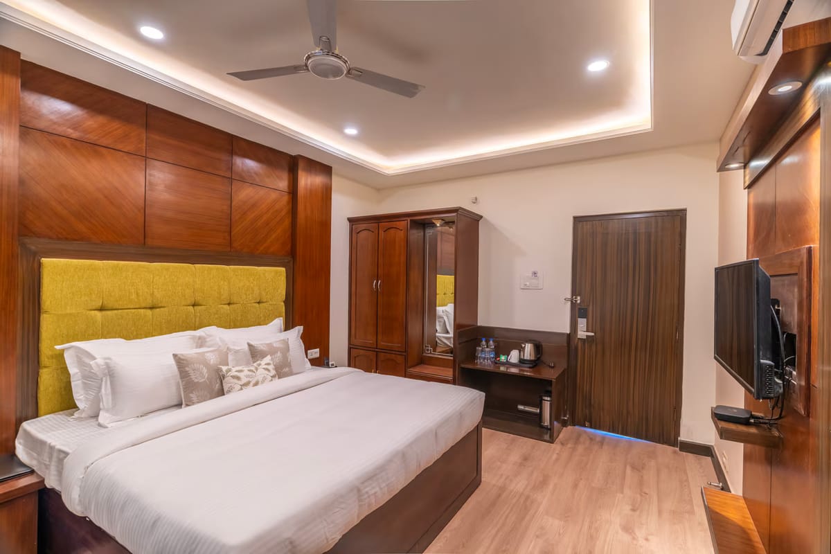 A Standard room with mountain view at Hotel Karnika, with a yellow padded headboard set into timber panelling