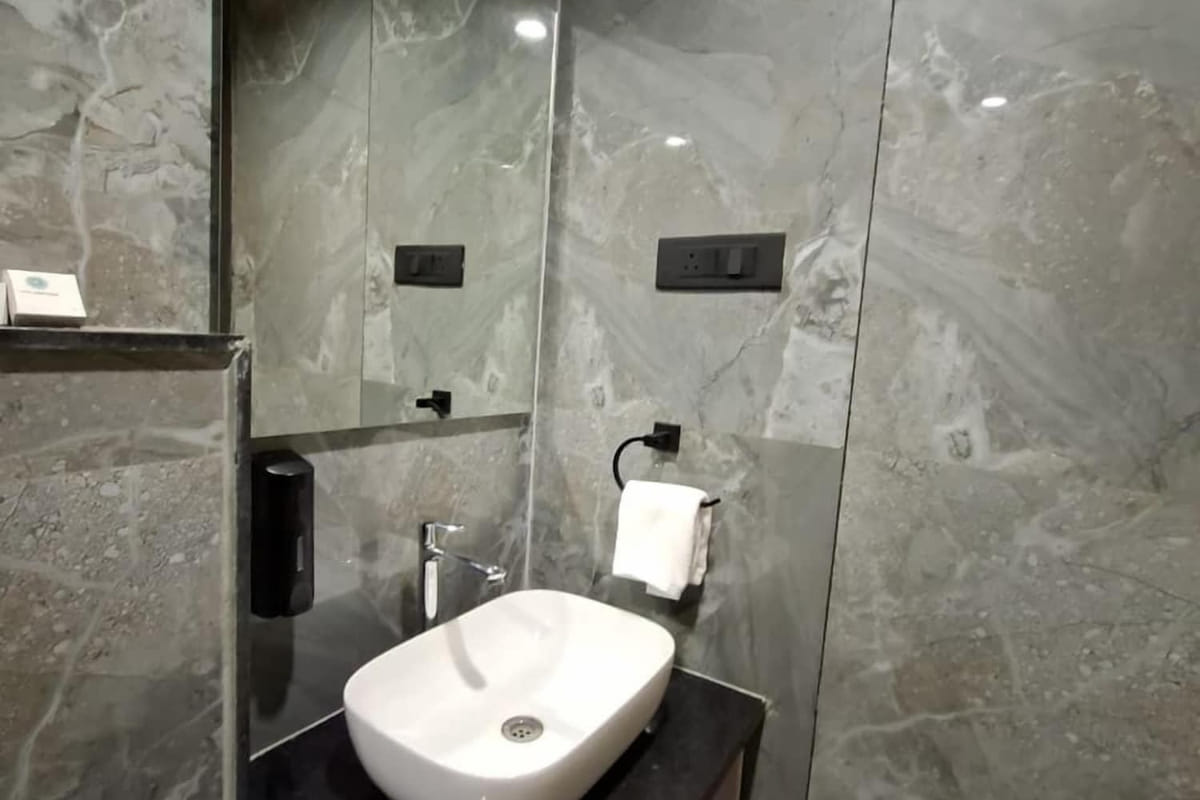 The washbasin in a guest bathroom at Hotel Shree Radhe By White Panda, set on a dark stone counter