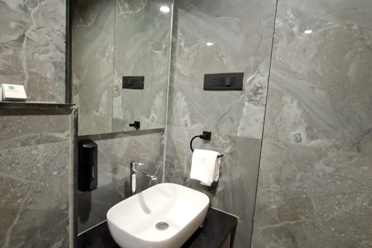 The vanity in a guest bathroom at Hotel Shree Radhe By White Panda, with the basin on a dark counter, a mirror