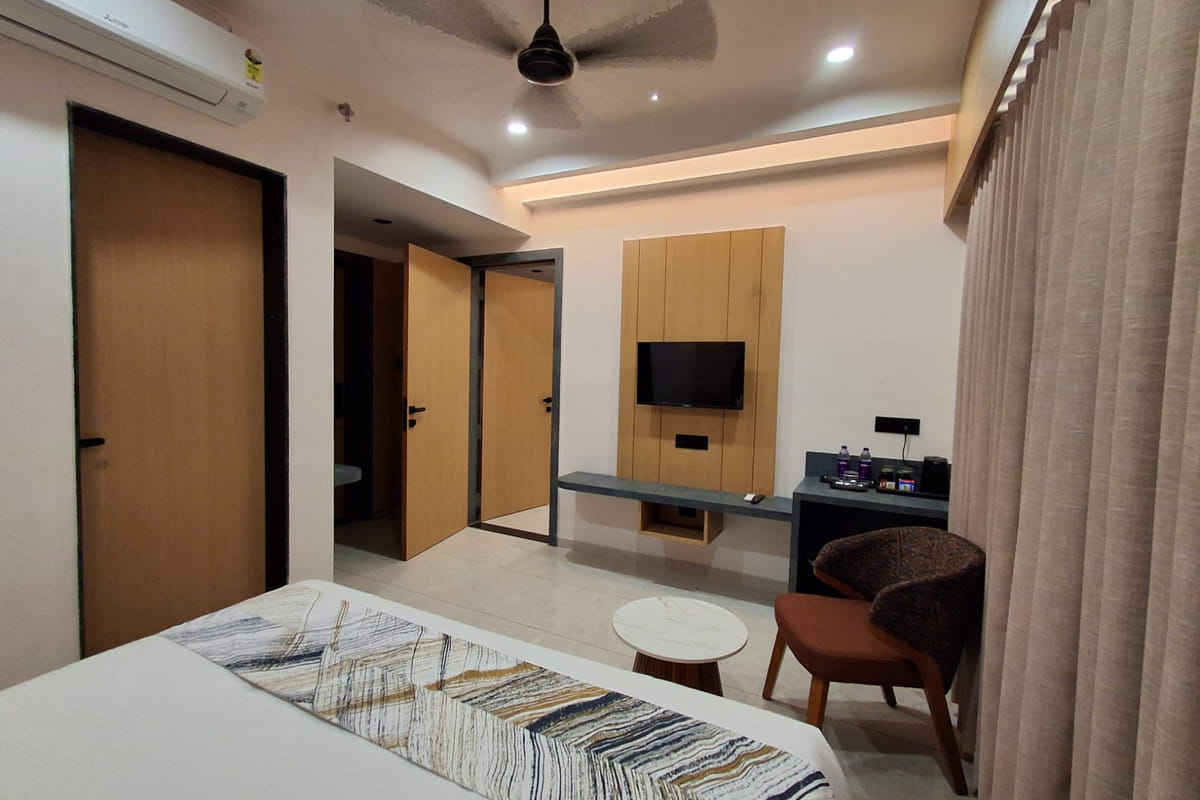 A guest room at Hotel Shree Radhe By White Panda, with a wardrobe beside the entrance door, a television on the timber panel