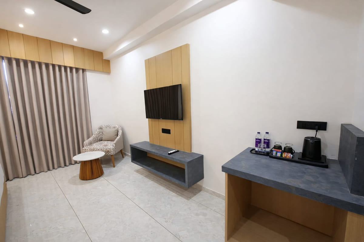 A guest room at Hotel Shree Radhe By White Panda, with a television above a long console, a work counter with a tray on it