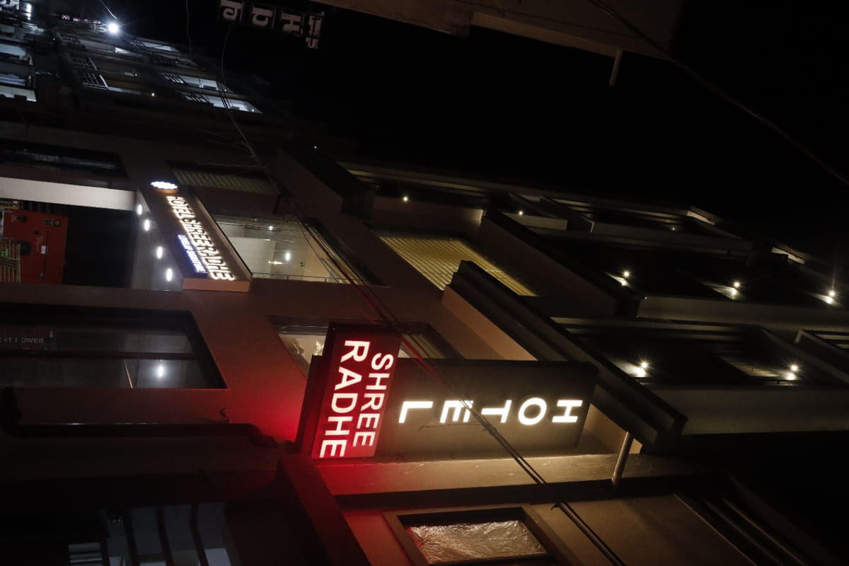 The illuminated Shree Radhe sign on the front of Hotel Shree Radhe By White Panda in Dwarka, glowing red
