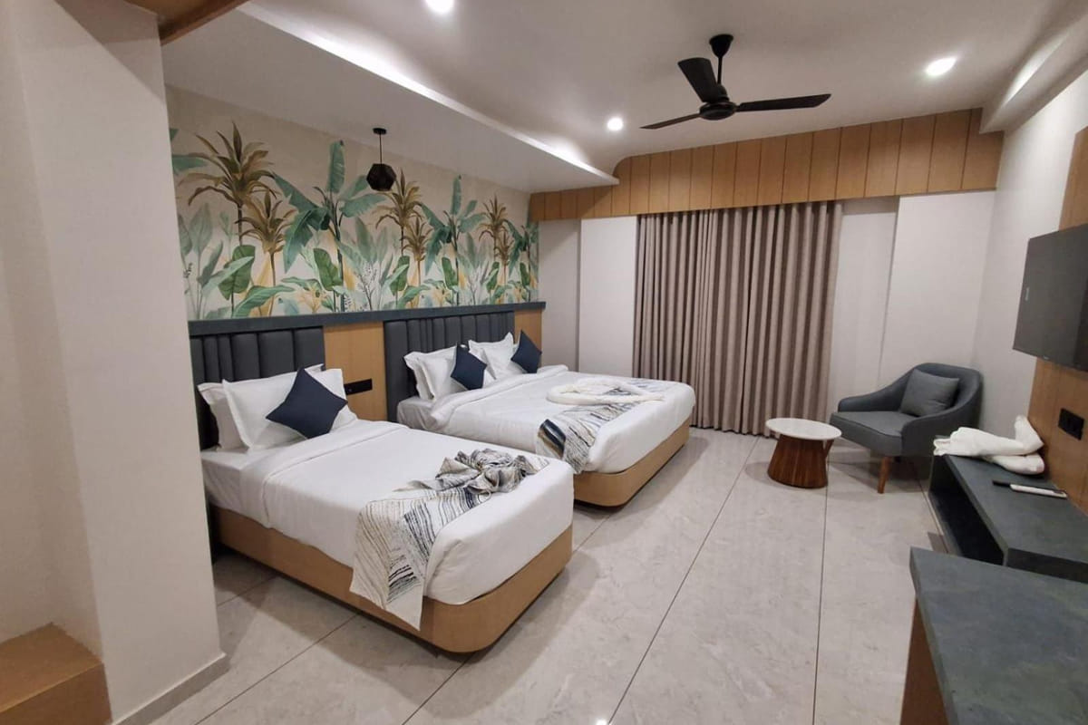 The Family Interconnected room at Hotel Shree Radhe By White Panda, with two beds side by side, a botanical mural on the wall
