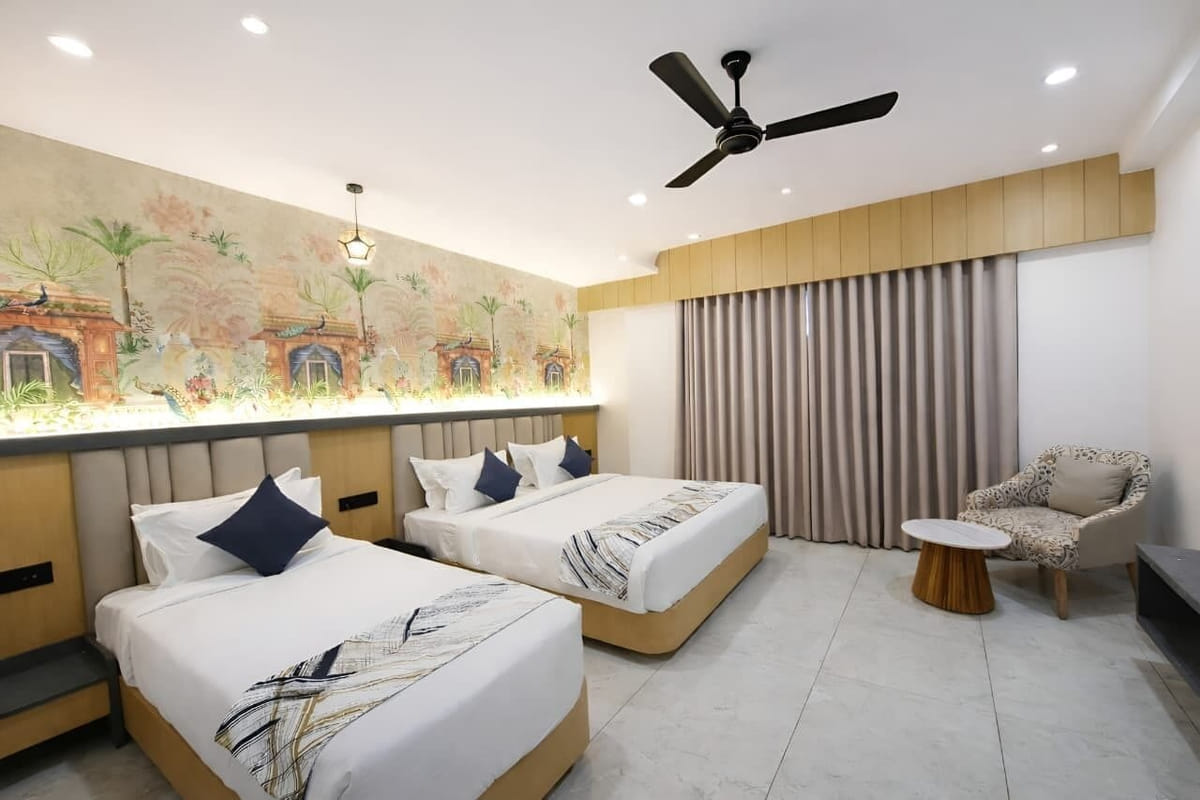 The Family Interconnected room at Hotel Shree Radhe By White Panda, with two beds below a painted mural of arches