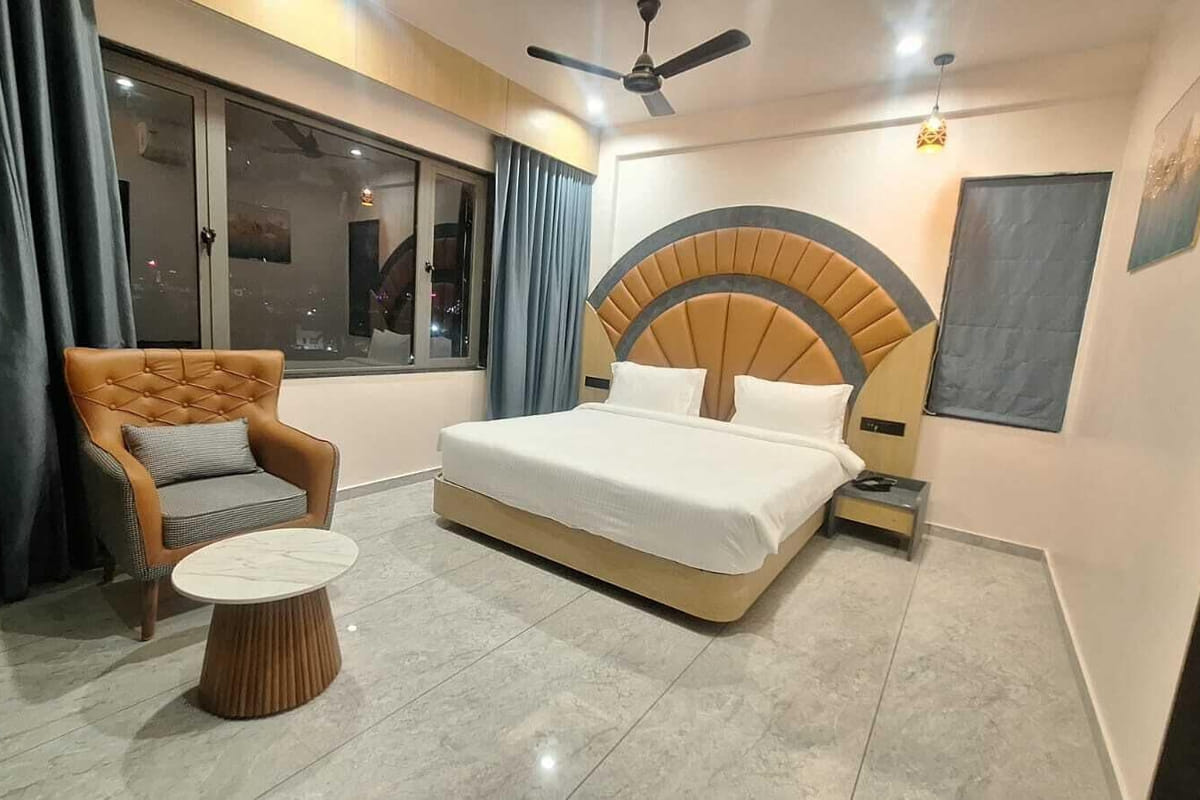 A Super Deluxe room at Hotel Shree Radhe By White Panda, with a fan-shaped padded headboard, a tufted armchair
