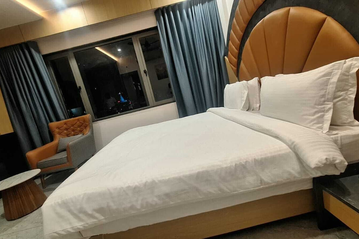 A Super Deluxe room at Hotel Shree Radhe By White Panda, the bed set against its fan-shaped padded headboard with the window