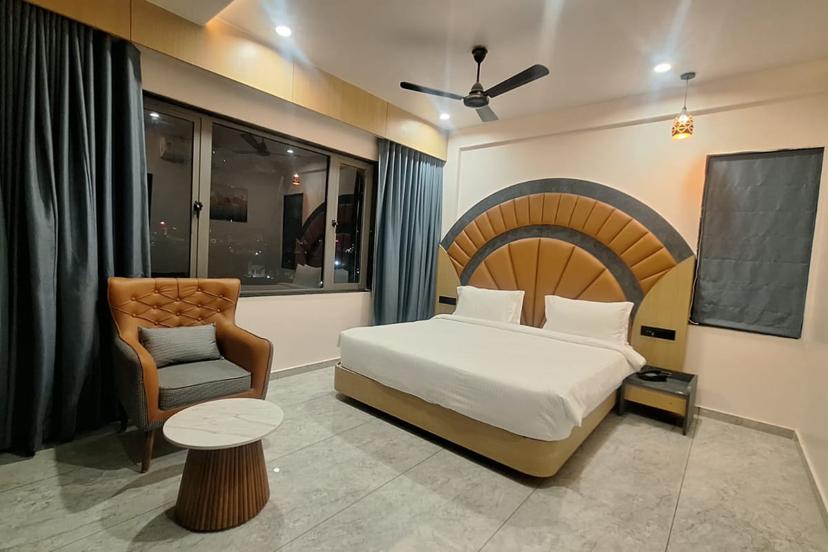 A Super Deluxe room at Hotel Shree Radhe By White Panda, seen from the doorway with the fan-shaped headboard, an armchair