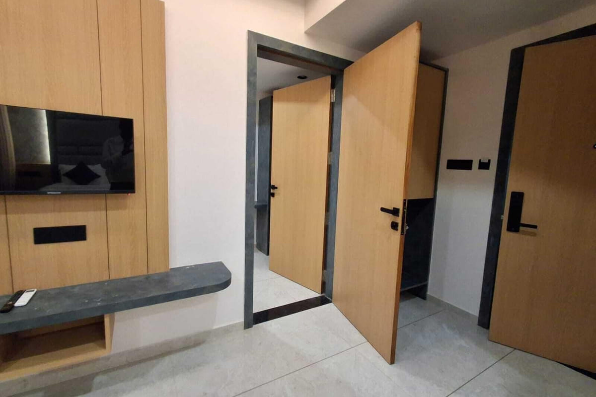 The entrance area of a guest room at Hotel Shree Radhe By White Panda, with a television on the timber panel