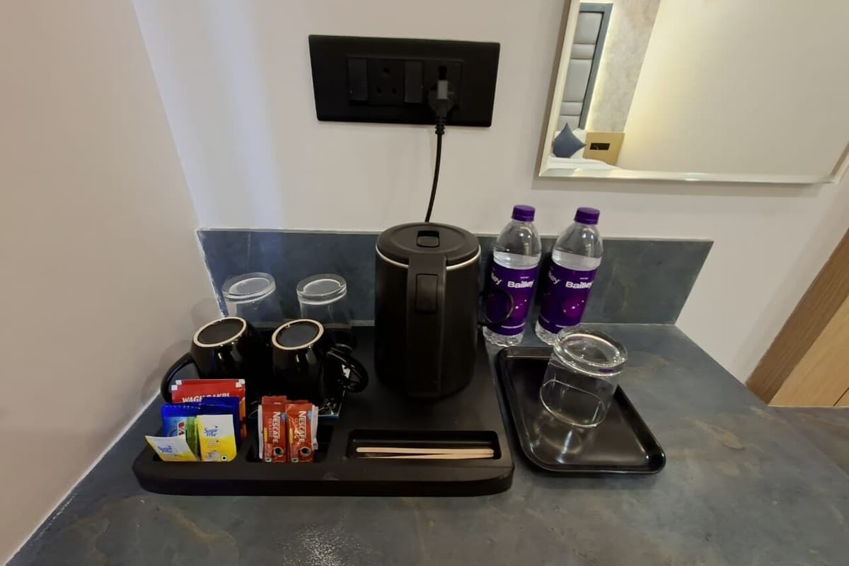 The tea and coffee tray in a guest room at Hotel Shree Radhe By White Panda, with a kettle, cups, sachets