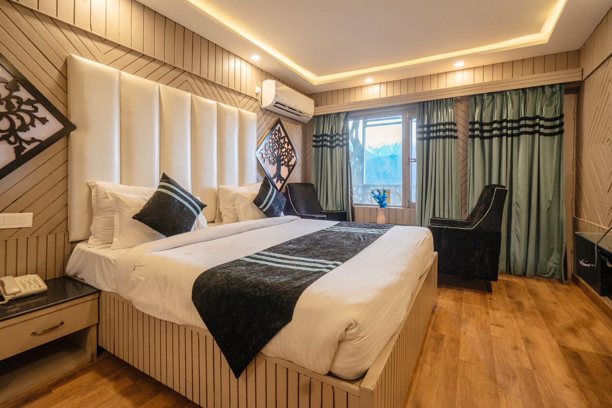 A King room with balcony at Levelup The Heritage Kud, with a tall padded headboard, timber panelling and armchairs