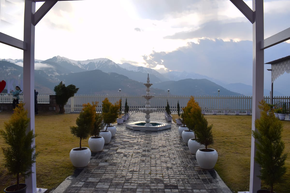 The lawn and fountain at Levelup The Heritage Kud in Patnitop, seen from under the pergola