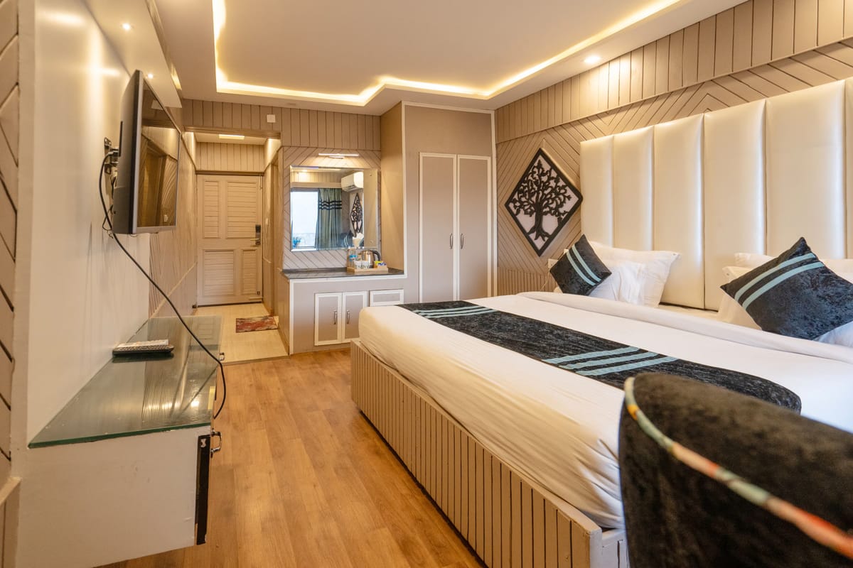 A King room with balcony at Levelup The Heritage Kud, with padded headboard panels, a wall-mounted television