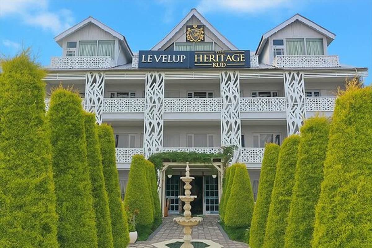 The white gabled frontage of Levelup The Heritage Kud in Patnitop, its signage above the balconies with clipped conifers
