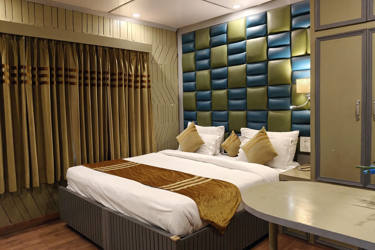 A Family room at Levelup The Heritage Kud, with a panelled headboard wall in green and blue, a gold runner across the bed