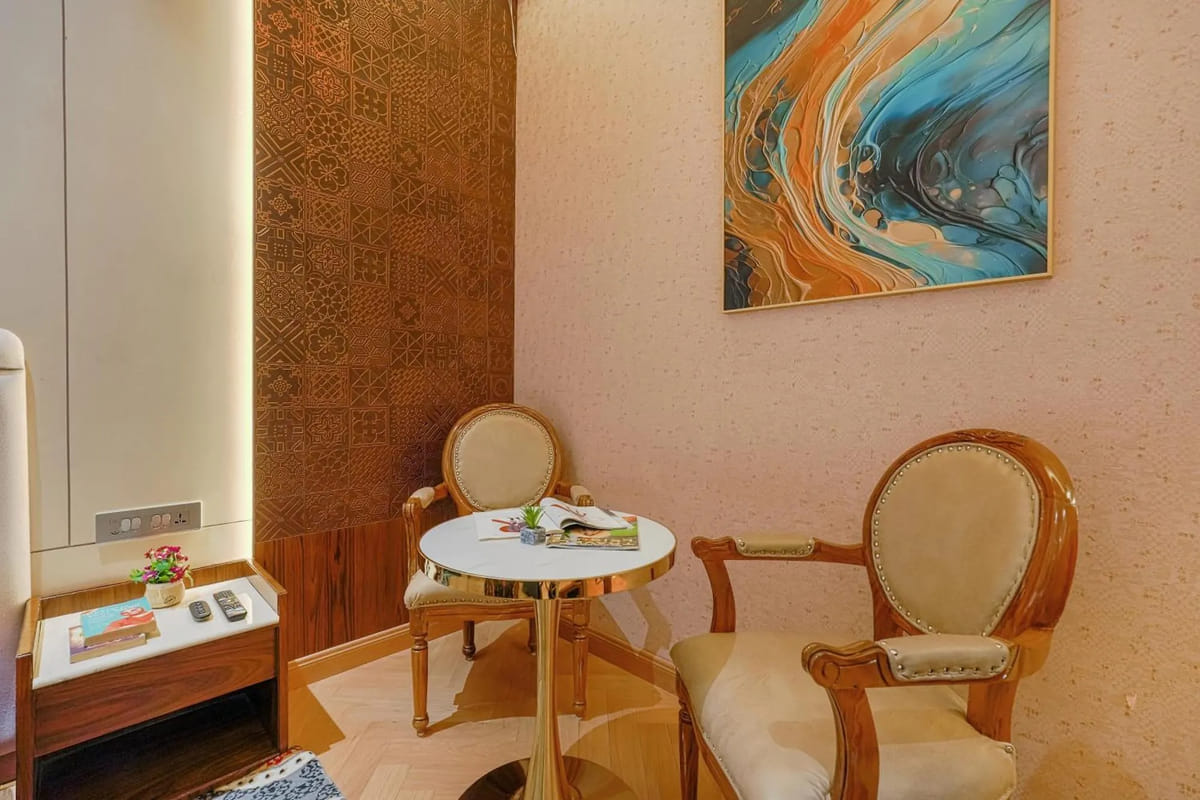 The seating corner of a Deluxe room at Marrion Hotel, with two carved armchairs around a small round table