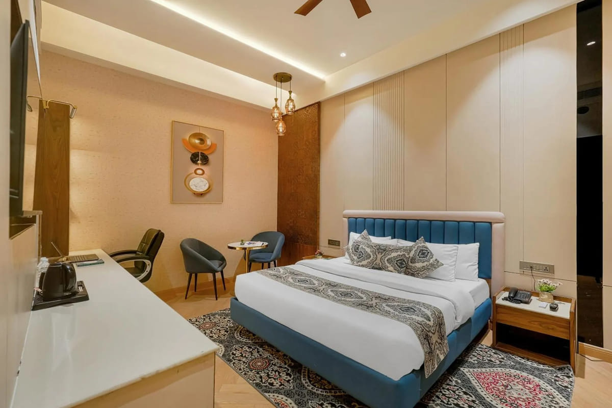 A guest room at Marrion Hotel, with a blue upholstered bed on a patterned rug, pendant lights over the bedside table