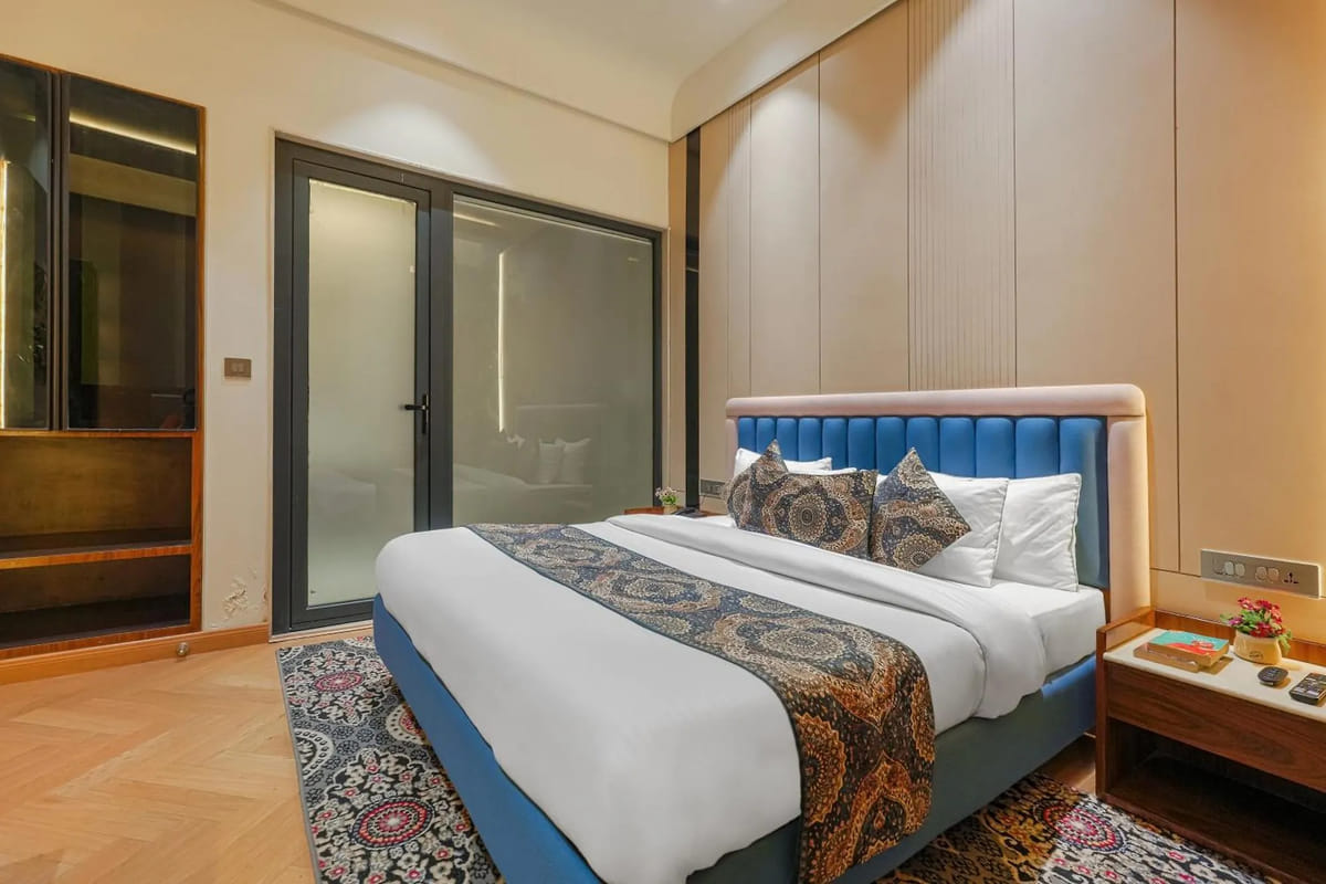 A guest room at Marrion Hotel, with a blue upholstered bed on a patterned rug, a fluted wardrobe wall