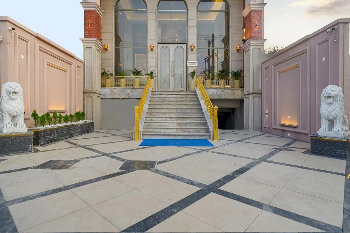 The paved entrance courtyard at Marrion Hotel, Amritsar, with gold handrails on the steps up to the glass doors