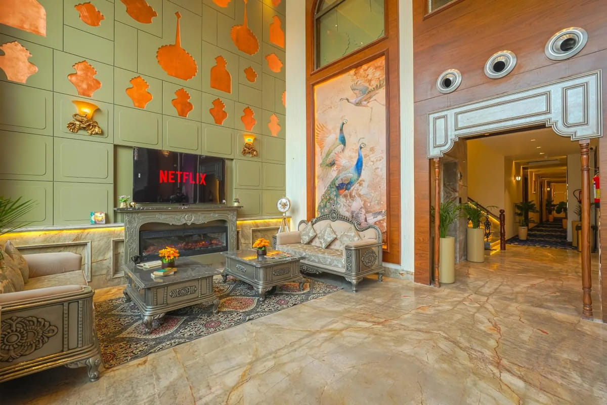The lobby lounge at Marrion Hotel, with a fireplace below a wall-mounted television, carved silver sofas