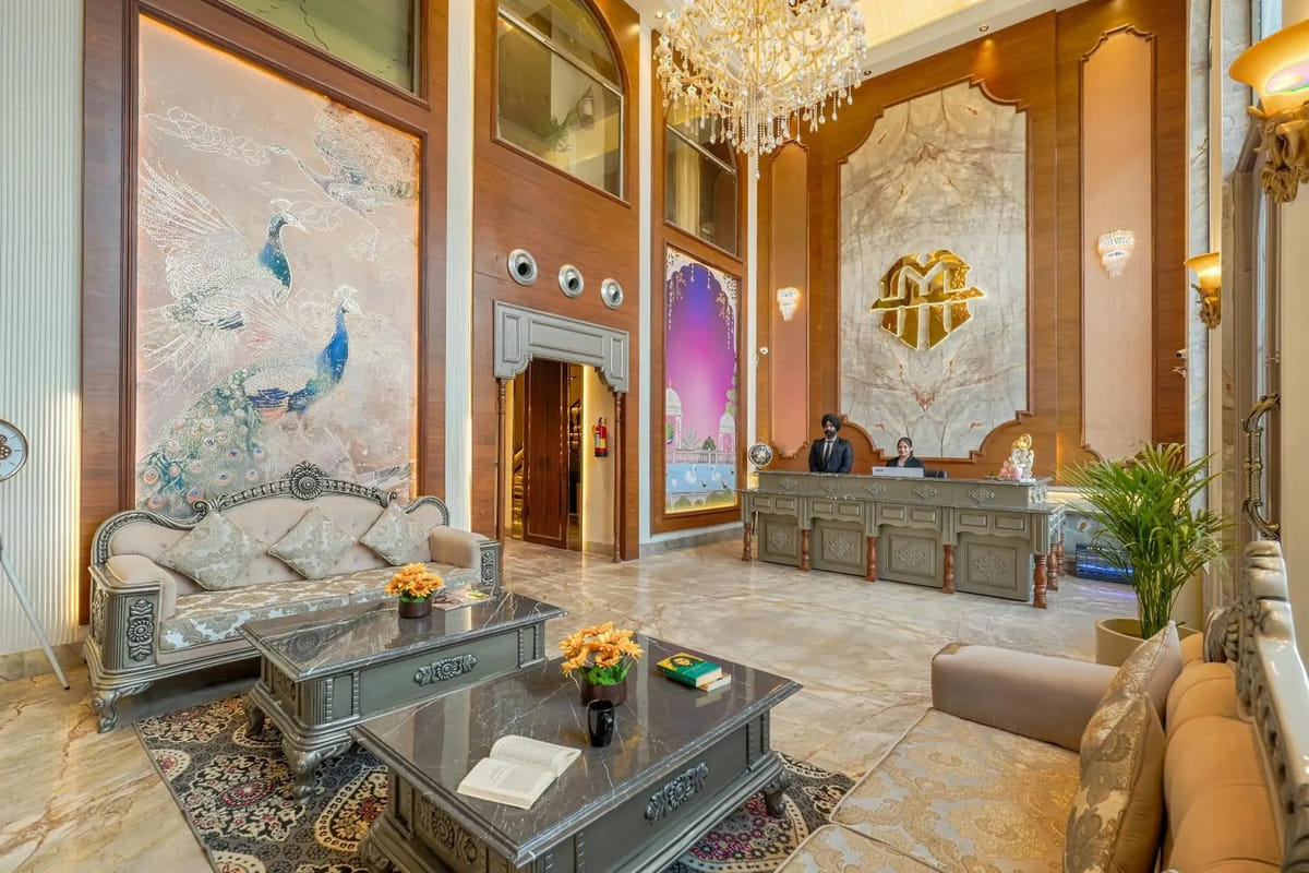 The double-height reception lobby at Marrion Hotel, with staff at the marble desk, a chandelier overhead and a peacock mural