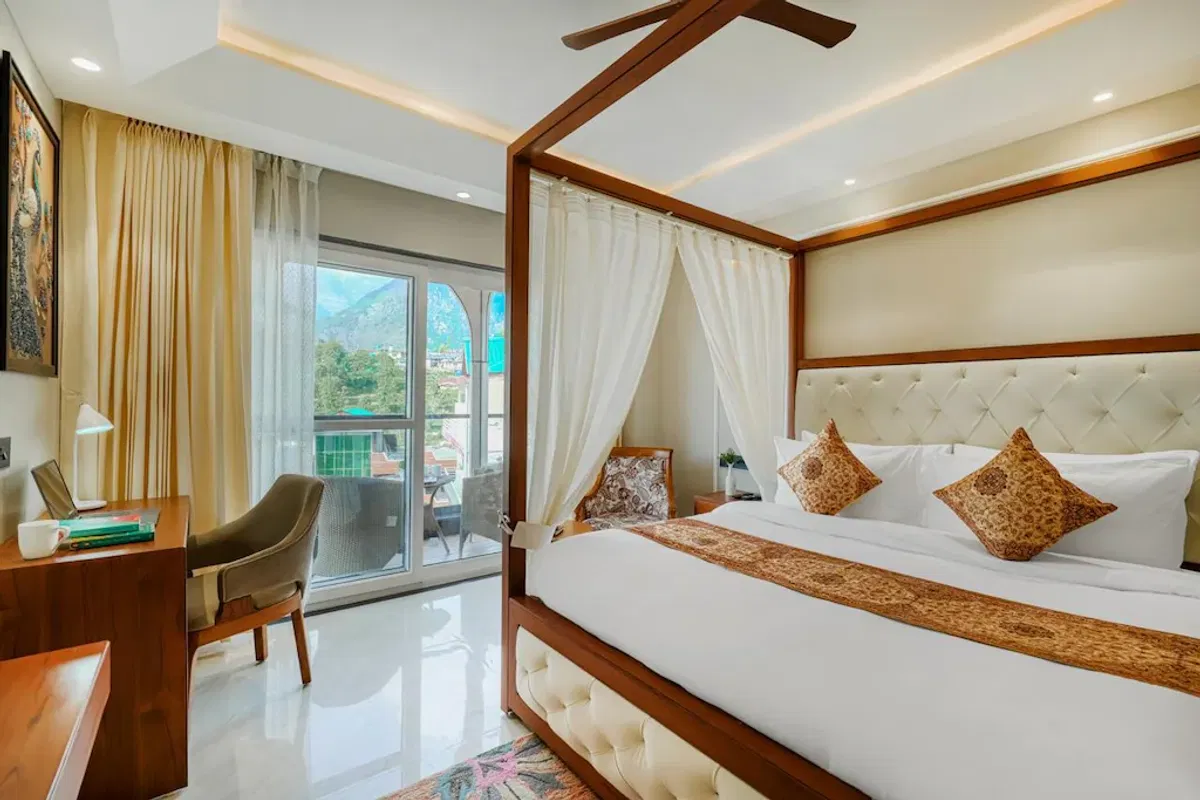 A guest room at White Panda Hotel Divine Peaks, with a draped four-poster bed, a writing desk