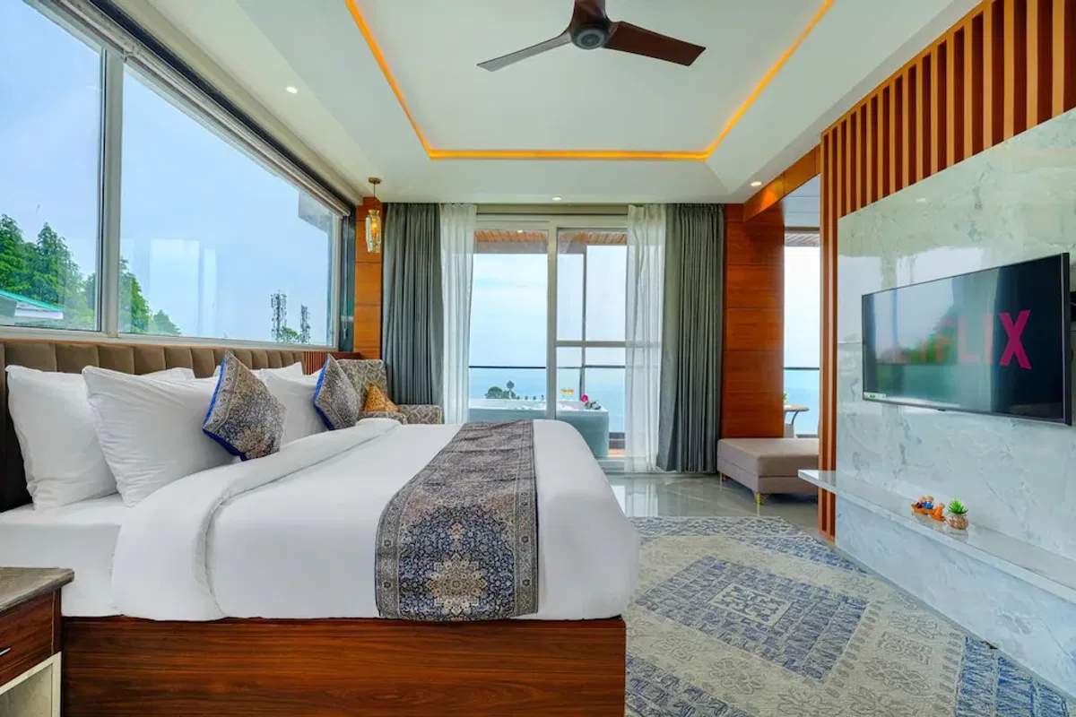 A guest room at White Panda Hotel Divine Peaks, with a patterned runner across the bed, wide valley windows