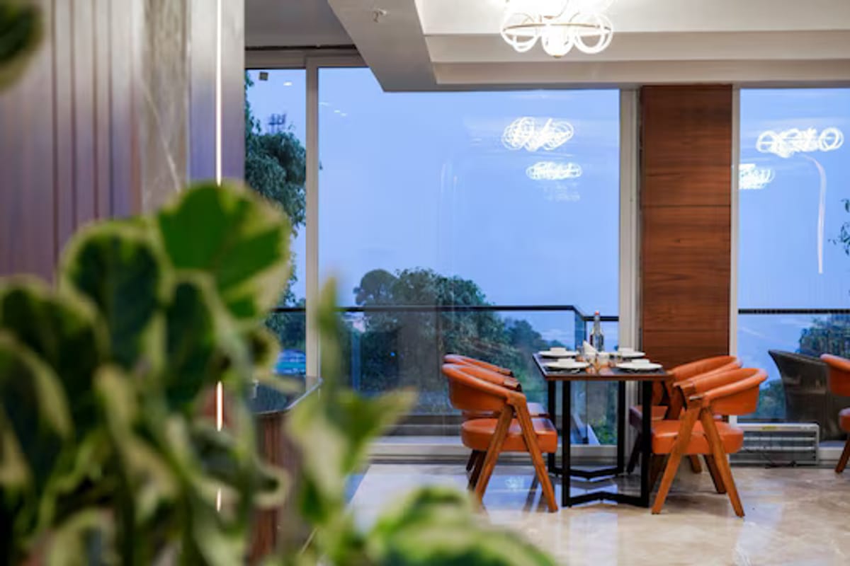 The dining room at White Panda Hotel Divine Peaks, with orange chairs drawn up to tables beside full-height windows