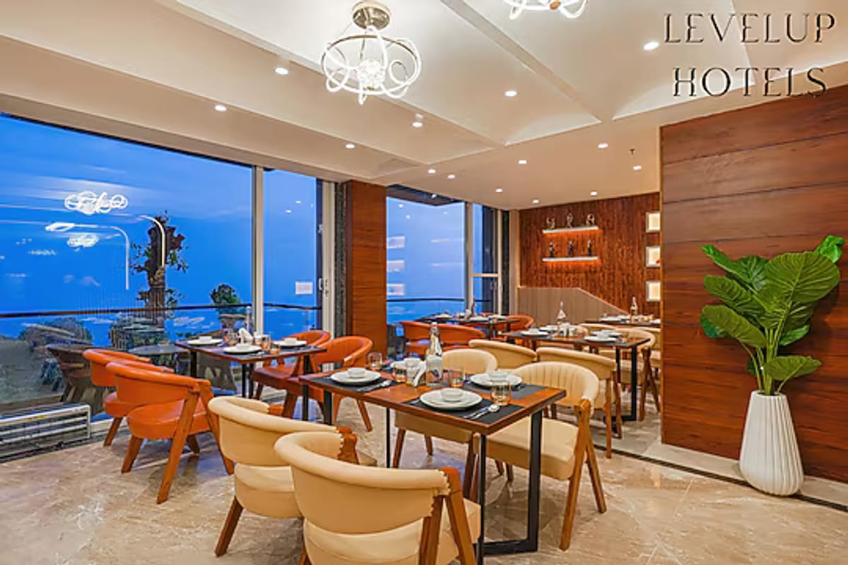 The restaurant at White Panda Hotel Divine Peaks, with rows of tables and orange chairs set along full-height windows