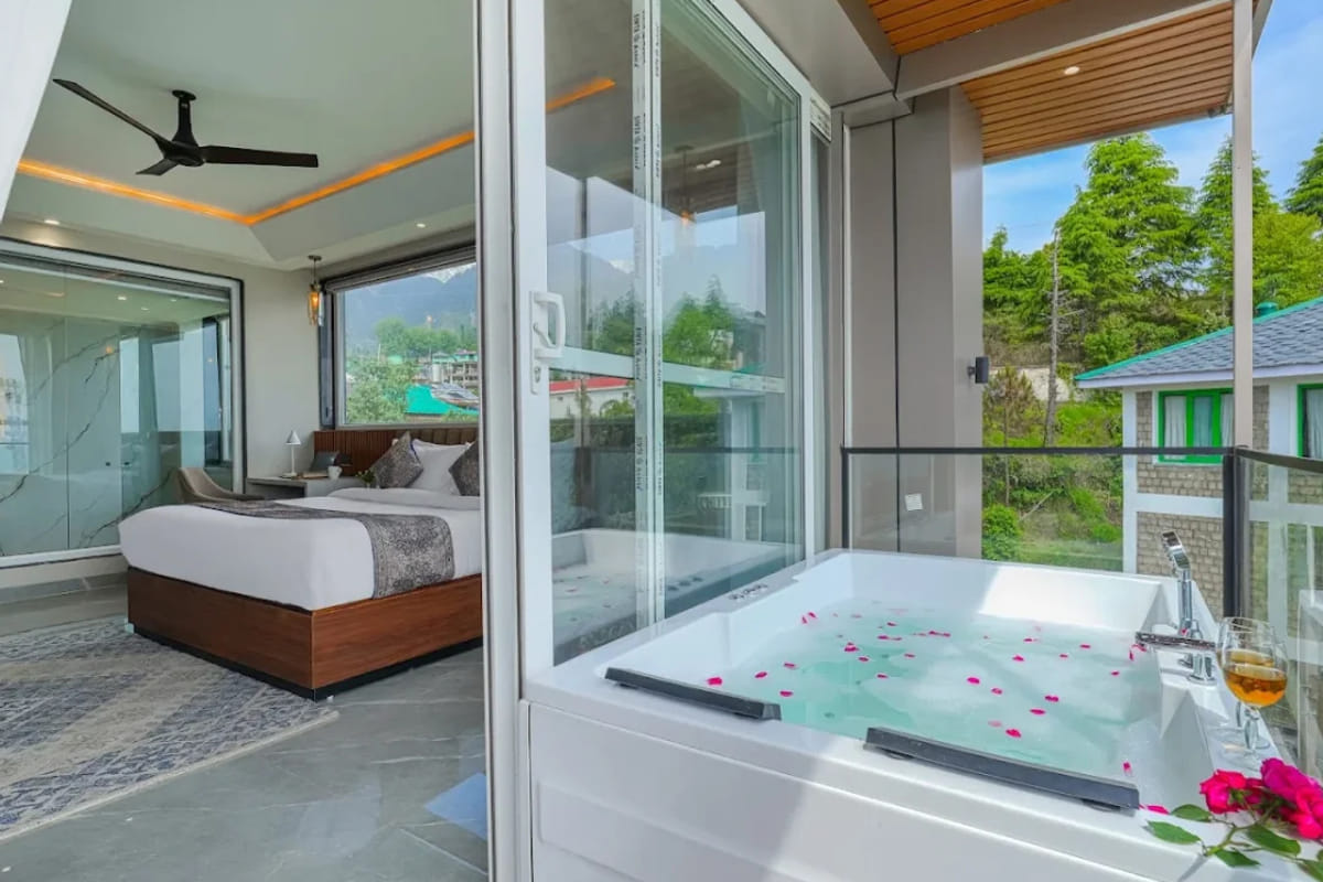 The Jacuzzi Suite Room at White Panda Hotel Divine Peaks, with a jacuzzi tub scattered with rose petals beside a glass wall