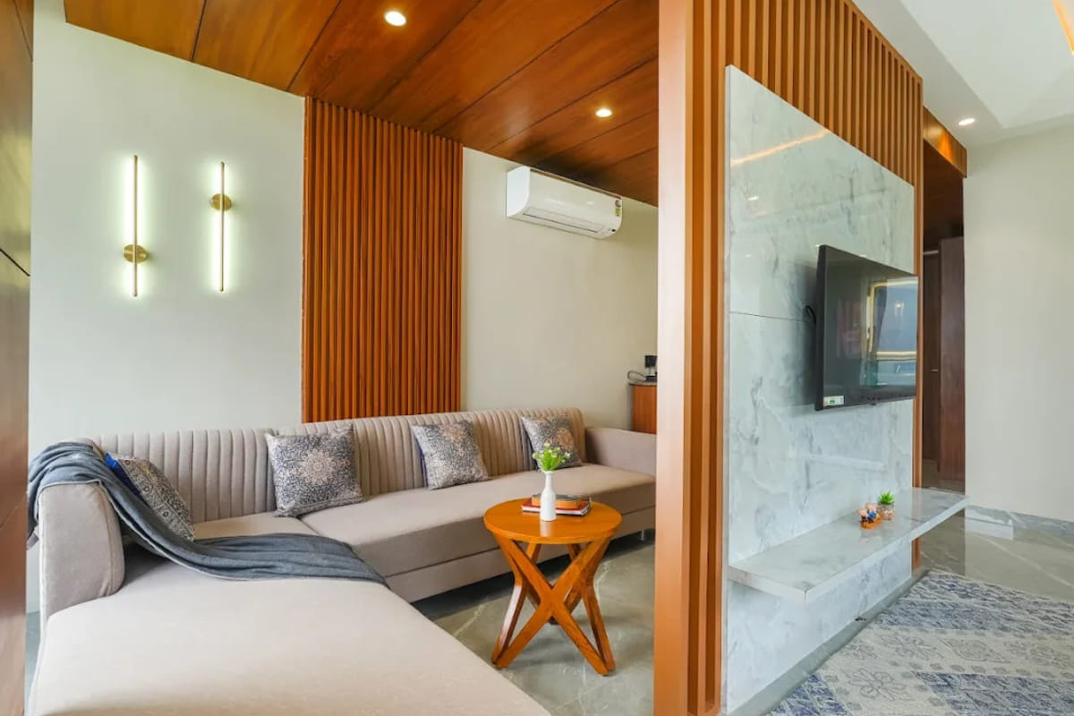 The living area of a suite at White Panda Hotel Divine Peaks, with an L-shaped sofa, a wall-mounted television