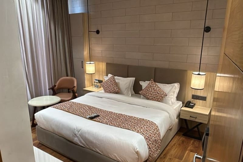 The Deluxe with City View at Amara Portico, with tall reading lamps either side of the bed and an armchair beside the window