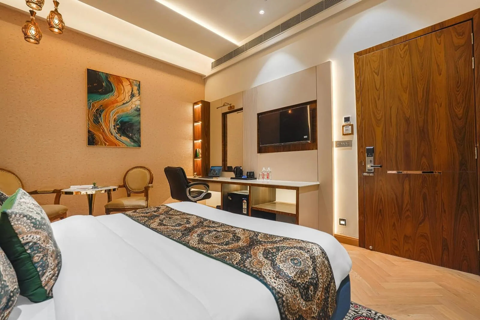 A guest room at Marrion Hotel, with a seating corner below an abstract painting, a long desk and television