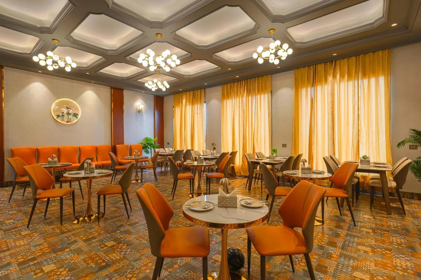 The restaurant at Marrion Hotel, set with orange chairs around round tables under sputnik chandeliers