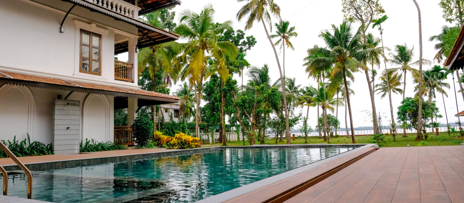 Full-length view of the Sanskreti infinity pool with palms on either side leading to the Vembanad backwaters